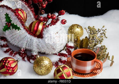 Wohnkultur Santa und seinem Schlitten auf Schnee Baum Dekorationen Tisch setzen und begleitet von einer warmen Tasse Kaffee Stockfoto