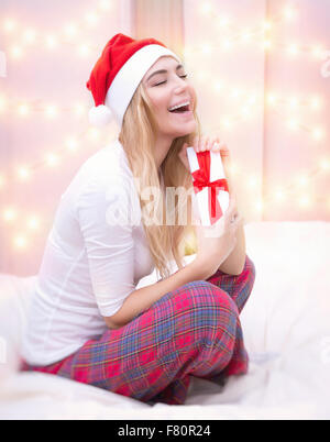 Schön aufgeregt Weibchen tragen rote Weihnachtsmütze mit geschlossenen Augen vorhanden, glücklich festliche Weihnachtsmorgen genießen Stockfoto