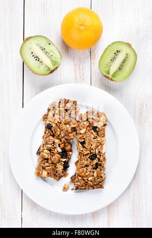 Müsliriegel auf weißen Teller und frisches Obst, Ansicht von oben Stockfoto