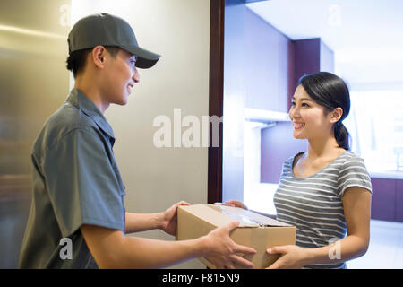 Junge Frau, die immer einer Pakets vom Zusteller Stockfoto