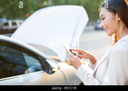 Fahrerin messaging auf dem Handy neben dem Auto kaputt Stockfoto