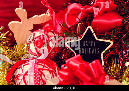 sternförmige Tafel mit dem Text Frohe Festtage, umgeben von einem Haufen von Geschenken und einigen anderen Weihnachtsschmuck, solche Stockfoto