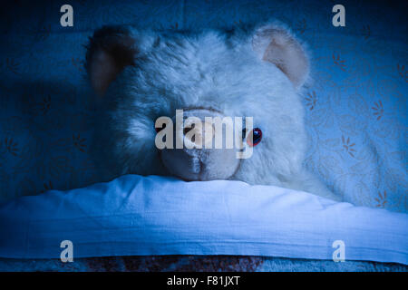 Zerstörten alten Teddy legen auf einem Bett in der Nacht Stockfoto