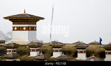 Ein einsamer Mann starrte auf eine der 108 Stupas am Dochula Pass an einem nebeligen Tag Stockfoto