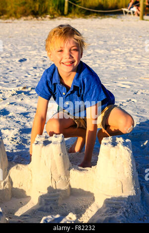 Kleiner Junge posiert bei Sonnenuntergang durch die Sandburg gebaut sie am Siesta Key Beach in Florida Stockfoto