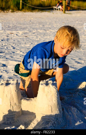 Kleiner Junge posiert bei Sonnenuntergang durch die Sandburg gebaut sie am Siesta Key Beach in Florida Stockfoto