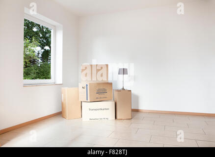 viele Umzugskartons stehen in einem leeren weißen Raum Stockfoto