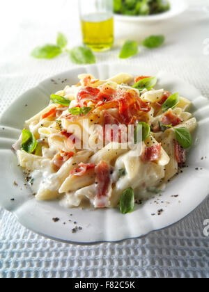 Frisch gekochter Pene Speck und Käse Carbonara, überzogen und mit Basilikum garniert Stockfoto