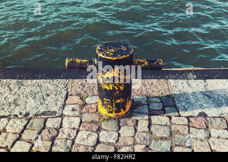 Alte gelbe Festmacher Poller auf Stein pier Stockfoto