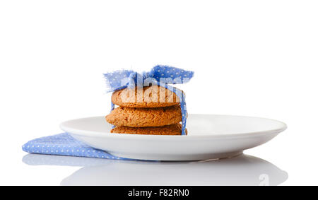 Stapel von drei hausgemachte Haferkekse gebunden mit blauem Band in kleine weiße Tupfen auf weißen Keramikplatte Stockfoto