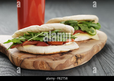 rustikale Sandwiches mit Schinken, Rucola und Tomaten im Fladenbrot auf Holztisch Stockfoto