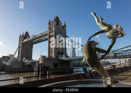 Mädchen und Dolphin Statue mit Tower Bridge hinter in London, UK Stockfoto