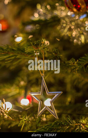 Ein Silver Star und bunten, glänzenden, glitzernden Christbaumschmuck Sekt auf einer grünen Sitka-Fichte-Tanne Stockfoto