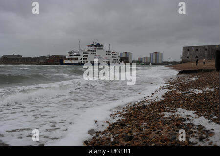 An einem stürmischen Tag Wellen auf den Strand als wightlink Fähren kommt in Portsmouth Harbour in Portsmouth, Hampshire, England. Stockfoto