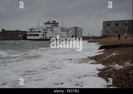 An einem stürmischen Tag Wellen auf den Strand als wightlink Fähren kommt in Portsmouth Harbour in Portsmouth, Hampshire, England. Stockfoto