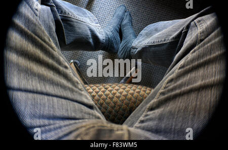 Mann in schmutzigen Jeans auf Stuhl sitzend Stockfoto