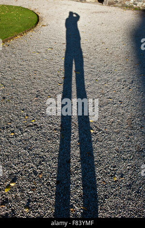 Lange Schatten eines Mannes auf Kies Kies selbst zu fotografieren Stockfoto