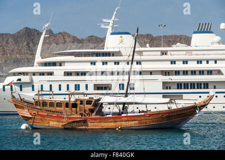 Holzboot vertäut neben der super-Yacht des Sultans von Oman im Hafen von Mutrah, Muscat. Stockfoto