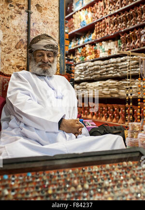 Omanische Mann sitzt vor seinem Geschäft in Mutrah Souk in Muscat, der Hauptstadt des Sultanats Oman. Stockfoto