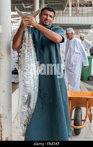 Omanische Mann posiert mit einem Fisch auf dem Fischmarkt Mutrah in Muscat, der Hauptstadt des Sultanats Oman. Stockfoto