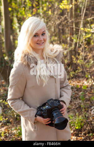 Hübsche blonde Frau mit einer DSLR-Kamera vor. Stockfoto