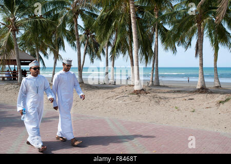 Zwei omanischen Männer zu Fuß entlang der Strandpromenade Qurum in Muscat, der Hauptstadt des Sultanats Oman. Stockfoto