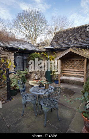 Britische Gärten. Einen kleinen abgeschiedenen Garten Terrasse mit Tisch und Stühlen. Stockfoto