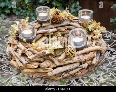 Weihnachten-Herzstück mit Holz und Kiefer Kegel, 4 Kerzen, Farben gold und braun, ausgesetzt auf Gartentisch erstellt. Stockfoto