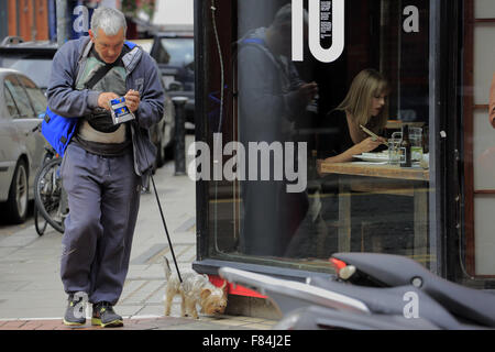 Eine junge Frau mit Stäbchen essen in einem Restaurant-Fenster mit einem Mann mit einem Hund zu Fuß durch. Dublin Irland Stockfoto