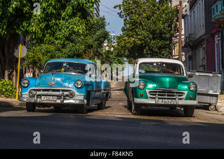 Ein paar alte Autos ziehen weg von einer Nebenstraße auf San Lazaro in Havanna. Stockfoto