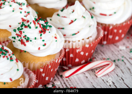 Weihnachten-Cupcakes mit Vanille Zuckerguss und rote und grüne Streusel auf Holztisch mit einer Zuckerstange Stockfoto