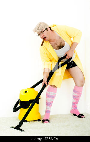 verrückte Teppich-Reiniger saugen mit Staubsauger im gelben Gewand Stockfoto