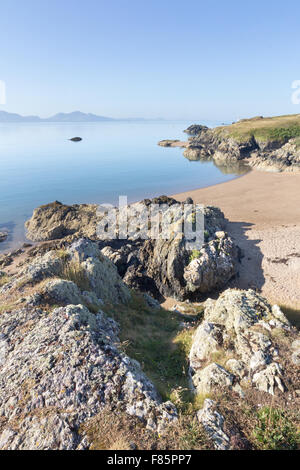 Vulkangestein und Strand auf Llanddwyn Island, Anglesey, Wales mit Halbinsel Llyn im Hintergrund Stockfoto