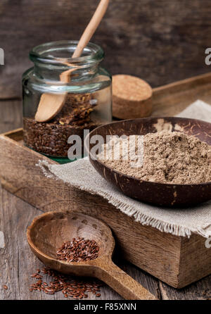 Leinsamen Mehl in eine Schüssel geben, jar Leinsamen in ein Glas auf einem hölzernen Hintergrund (glutenfreie Diät) Stockfoto