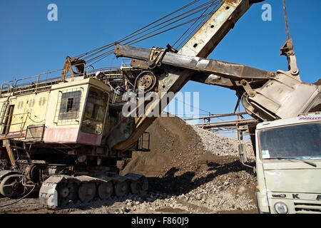 Bagger gießt Schutt in einem LKW Stockfoto