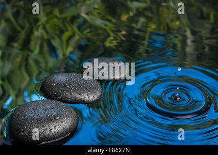 Drei Spa Stein Tropfen in das blaue Wasser liegen, kann als Hintergrund verwendet werden Stockfoto