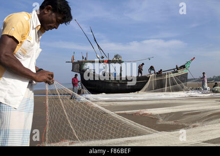 29. November 2015 - Cox Bazar, Bangladesch - COX BAZAR, Bangladesch - November 29:Fisher Mann von Klimawandel und den Meeresspiegel ansteigen Bereich reparieren ihre Netze zum Fischfang im Meer in der Nähe von Kutubdia Islandof Cox Bazar Assistenten am 29. November, 2015.Kutubdia, eine Insel vor der Cox Bazar Küste. die Widrigkeiten der Natur ausgelöst vor allem durch Klima ändern. In den letzten zwei Jahrzehnten wurden die Auswirkungen des Klimawandels in Bangladesch Beschleunigung. Kutubdia ist auch schwer getroffen. Der Ort ist sehr anfällig für Wirbelstürme und Sturmfluten, die häufiger und intensiver in Bangladesch sowie steigende geworden sind Stockfoto