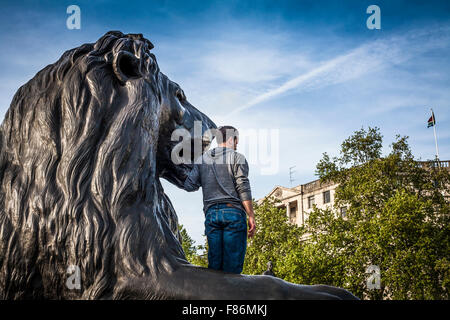 Mann klettert auf die Löwen am Trafalgar Square Stockfoto