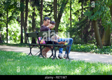 Lächelnde paar sitzt auf einem Park bench aussehen und Eichhörnchen (Lazienki-Park, Warschau, Polen) Stockfoto