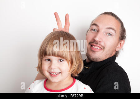 Junger Mann mit kleinen blonden kaukasische Mädchen, Studio-Porträt über weiße Wand Hintergrund Stockfoto