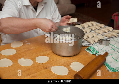 Ukrainischen Hause kochen füllt frisch gerollten Teig mit Kartoffelpüree zu traditionellen Piroggen. Stockfoto