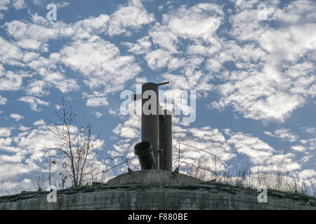 Metallstruktur des großen Stahlrohre auf Beton gegen den blauen Himmel mit Wolken Stockfoto