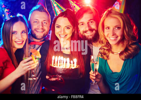 Fröhliche Freunde mit Geburtstagstorte im Nachtclub jubelt Stockfoto