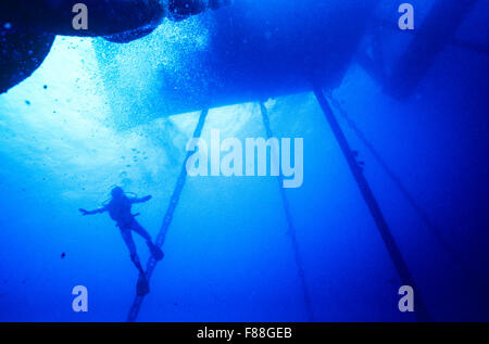 Scuba Diver Schwimmen unter Offshore Oil Rig, Thailand, Südostasien Stockfoto