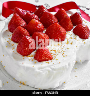 Nahaufnahme einer herzförmigen Kuchen mit Sahne und garniert mit Erdbeeren Stockfoto