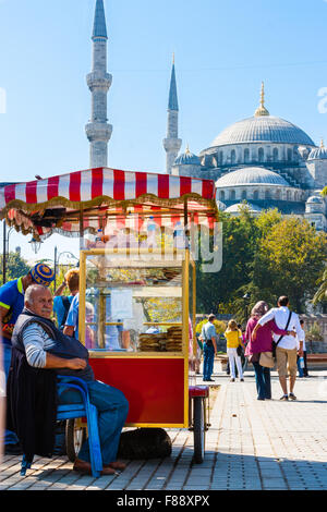 Ein türkischer Mann sitzt im Schatten neben seinem Stall vor der blauen Moschee in Istanbul, Türkei Stockfoto