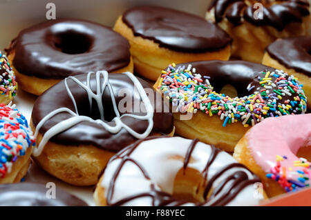 Bild von sortierten Donuts in einer Box mit Schokolade bereift, rosa glasiert und Streusel Donuts. Stockfoto