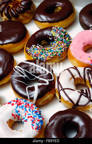 Bild von sortierten Donuts mit Schokolade bereift, rosa glasiert und Streusel Donuts. Stockfoto