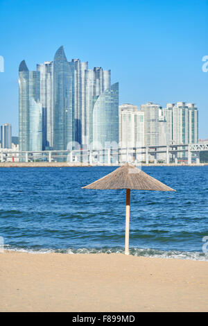 Strohschirm Gwangalli Beach mit modernen Gebäuden in Marinestadt. Gwangan Strand befindet sich westlich von Haeundae Strand in Busan Stockfoto