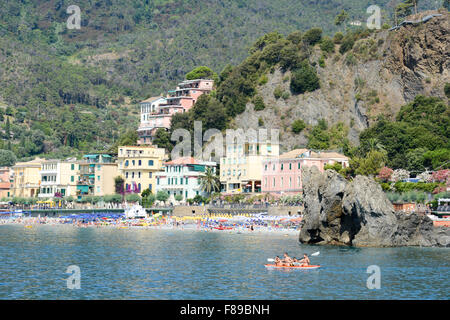 Monterosso, Italien - 7. Juli 2015: Menschen paddeln in einem Kanu, Schwimmen und Sonnenbaden am Strand von Monterosso auf Cinque Terre Stockfoto